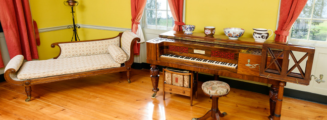 Piano and lounge chair inside a yellow room